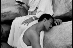 SAUDI ARABIA. Plain of Arafat. Hajj pilgrimage. 1991. A pilgrim reads the Koran on Mount Rahma, while his friend rests.